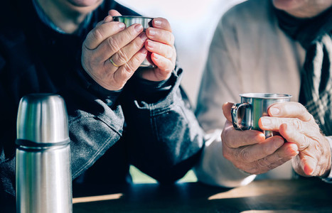Senior couple hands holding cups with hot coffee