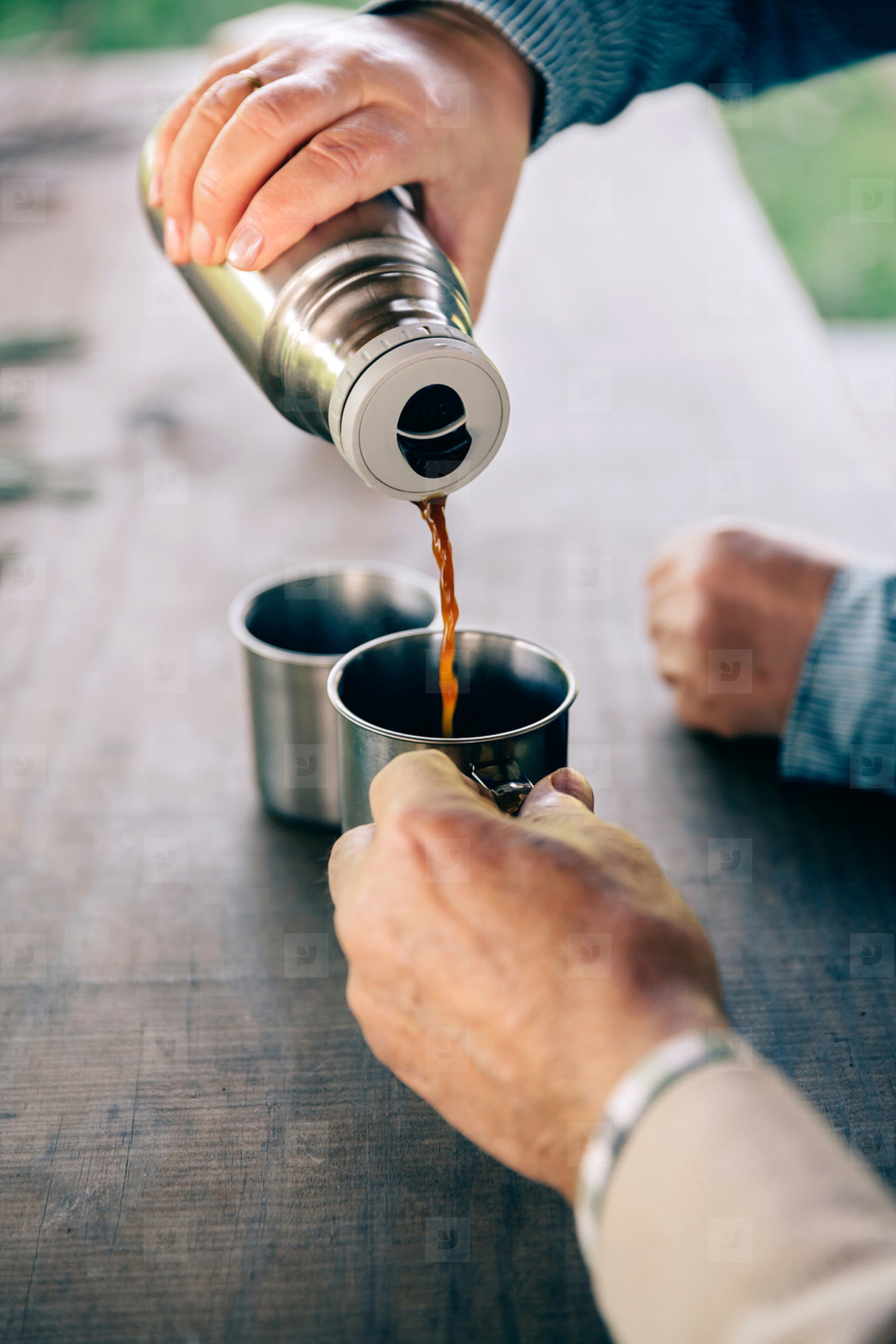 Senior couple hands pouring coffee from thermos