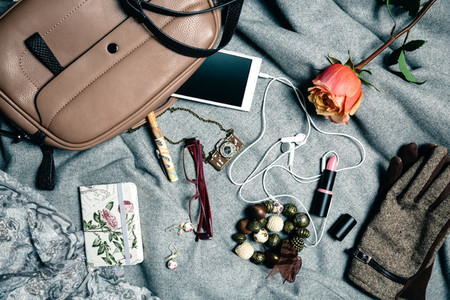 Feminine accessories from handbag over grey background