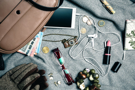 Feminine accessories from female handbag over grey background