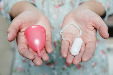 Woman holding tampon and menstrual cup in her hands