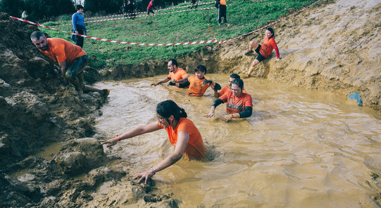 Runners crossing mud pit in a test of extreme obstacle race