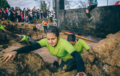 Runner crossing mud pit in a test of extreme obstacle race