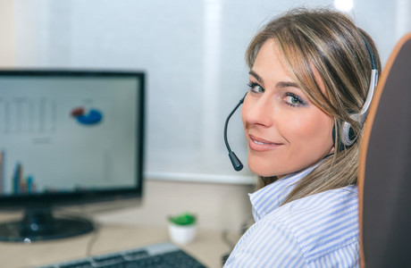 Smiling blonde secretary working with computer in office