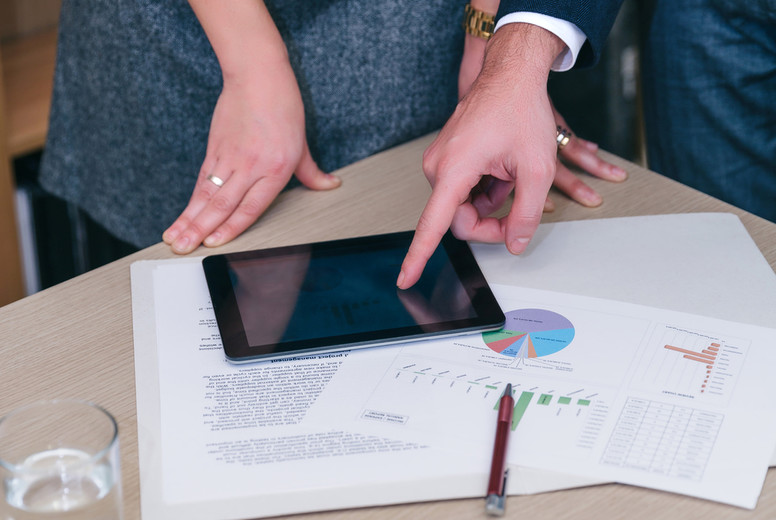 Unrecognizable colleagues using tablet and documents in meeting