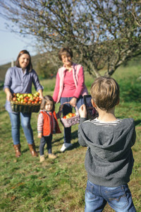 Boy taking photo to family with apples in basket