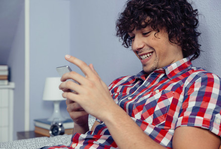 Young handsome man looking smartphone and laughing