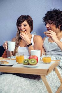 Couple having breakfast in bed served over tray