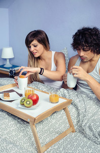 Couple having breakfast in bed served over tray