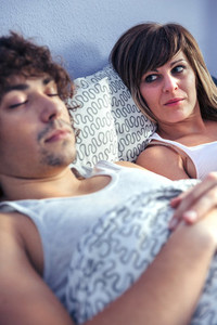Angry woman looking to young man sleeping