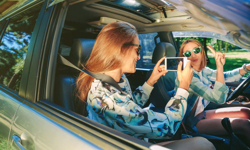 Woman taking photo to her friend inside of car