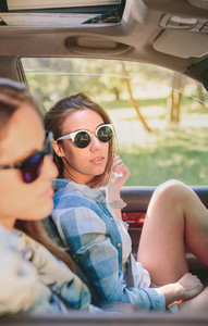 Two young women resting sitting inside of car
