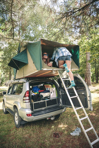 Woman walking up ladder to tent over car