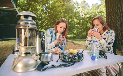 Women drinking cups of coffee in forest