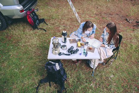 Young women looking road map in campsite