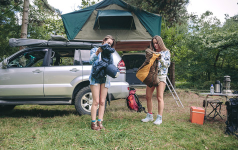 Young women opening sleeping bags in campsite