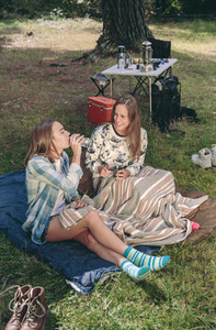 Woman drinking water with friend in campsite