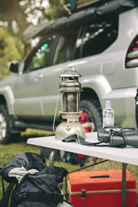 Oil lamp and binoculars over camping table