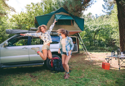 Young women having fun in campsite with 4x4 on background