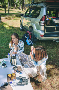 Woman playing harmonica with friend in campsite
