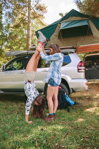 Woman helping to female friend doing handstand