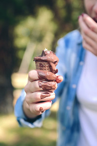 Young woman eating chocolate ice cream in forest