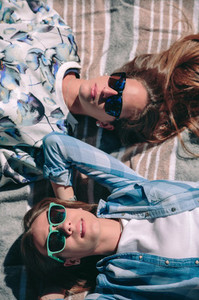 Two women with sunglasses lying taking a sunbath