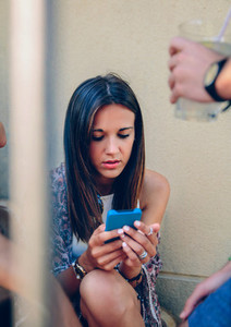 Young woman looking a smartphone outdoors with her friends
