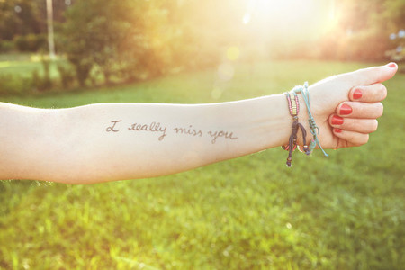 Female arm with text  I really miss you  written in skin