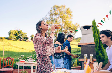 Woman drinking beer in a barbecue with friends