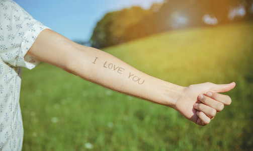 Male arm with text  I love you  written in skin