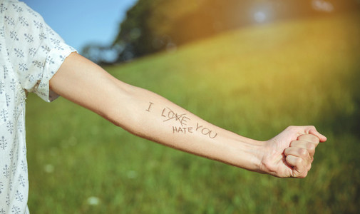 Male arm with text  I hate you  written in skin