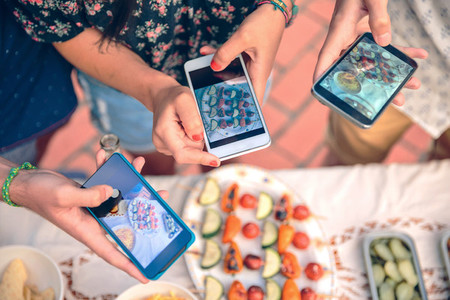 Young hands taking photos with smartphones to vegetable skewers
