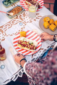 Woman holding plate with hot dog and corn