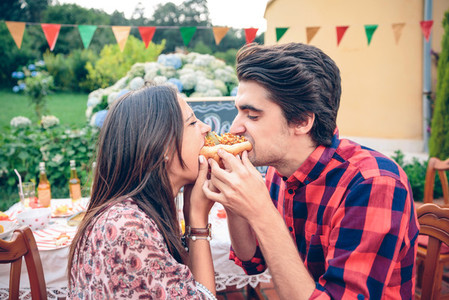 Funny young couple eating an american hot dog