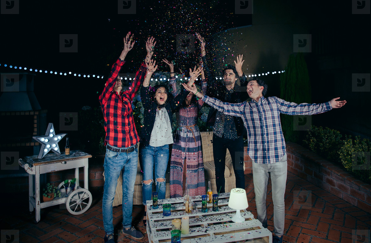 Happy friends having fun among the party confetti