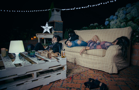 Young drunk friends sleeping in a sofa after party