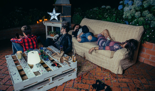 Young drunk friends sleeping in a sofa after party