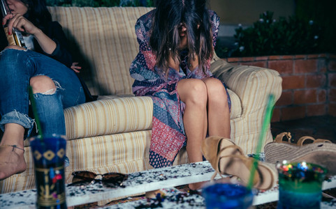 Young drunk woman sitting in the sofa on a party