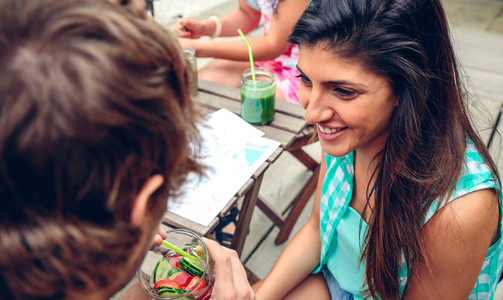 Smiling woman looking man drinking infused water cocktail