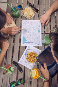Young tourist friends looking maps in over a table