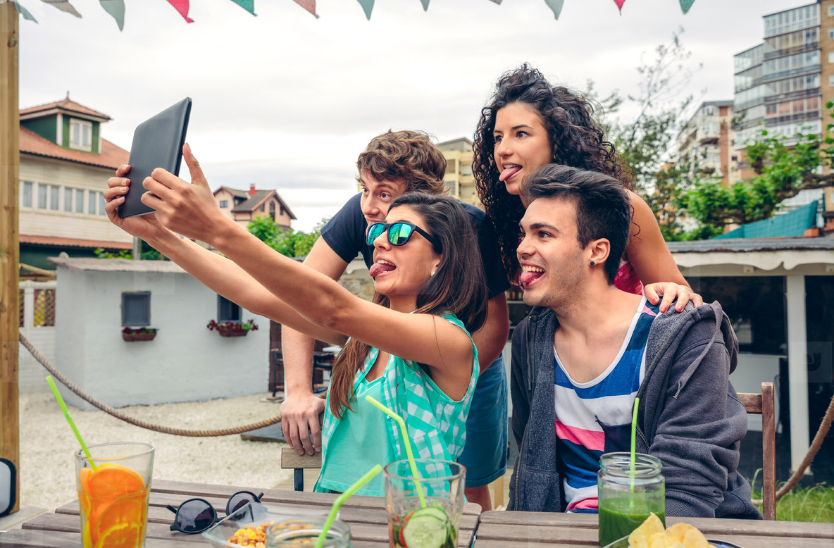 Young people taking a selfie with tablet in party