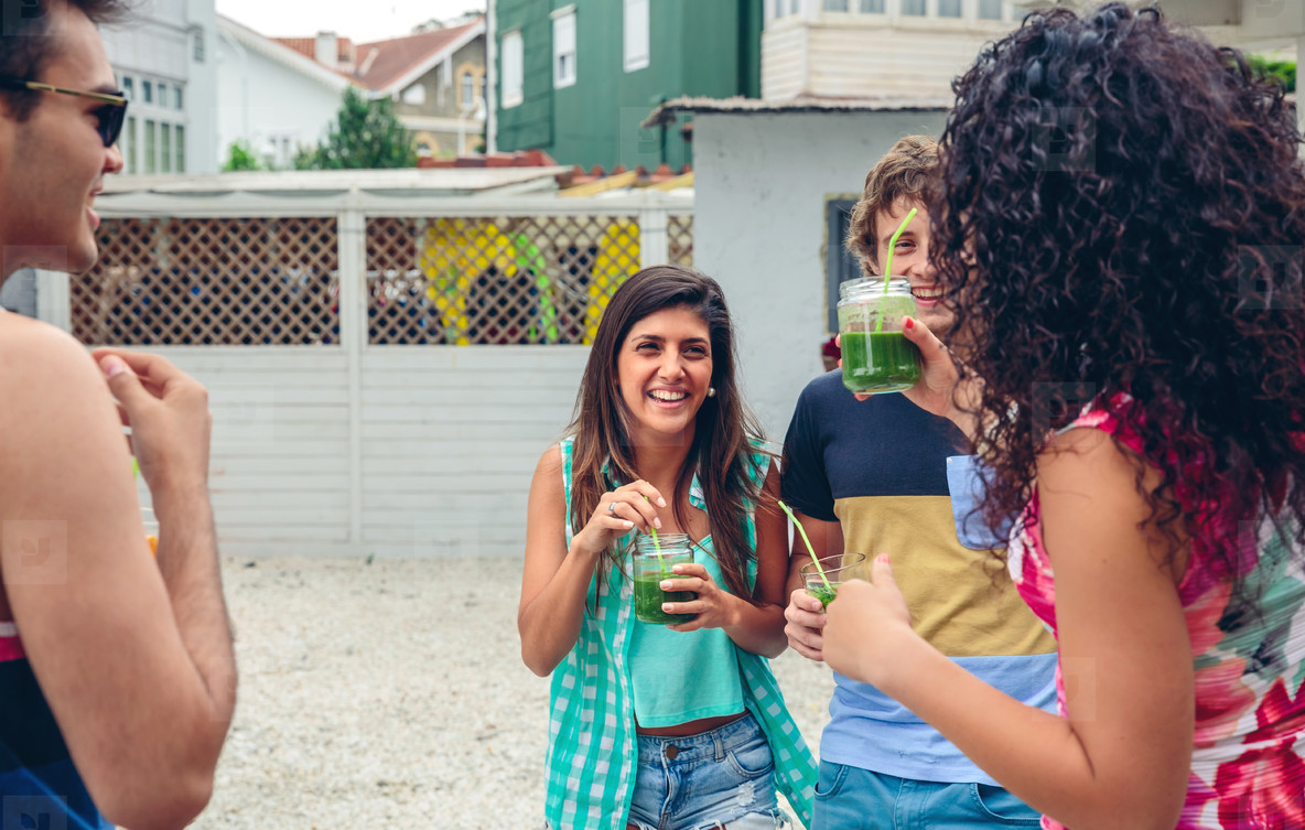 Happy people with beverages laughing in summer party