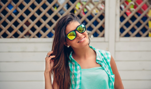Woman with sunglasses looking at camera over garden fence