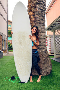 Surfer woman with bikini and wetsuit holding surfboard