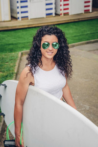 Brunette surfer woman with top holding surfboard