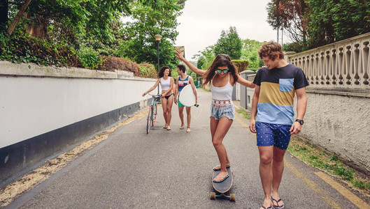 Happy young woman riding on skate with her friends