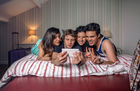 Young people taking a selfie lying over the bed