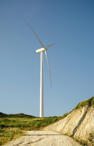 Wind turbine generating electricity over blue sky background