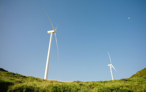 Wind turbines generating electricity over blue sky background